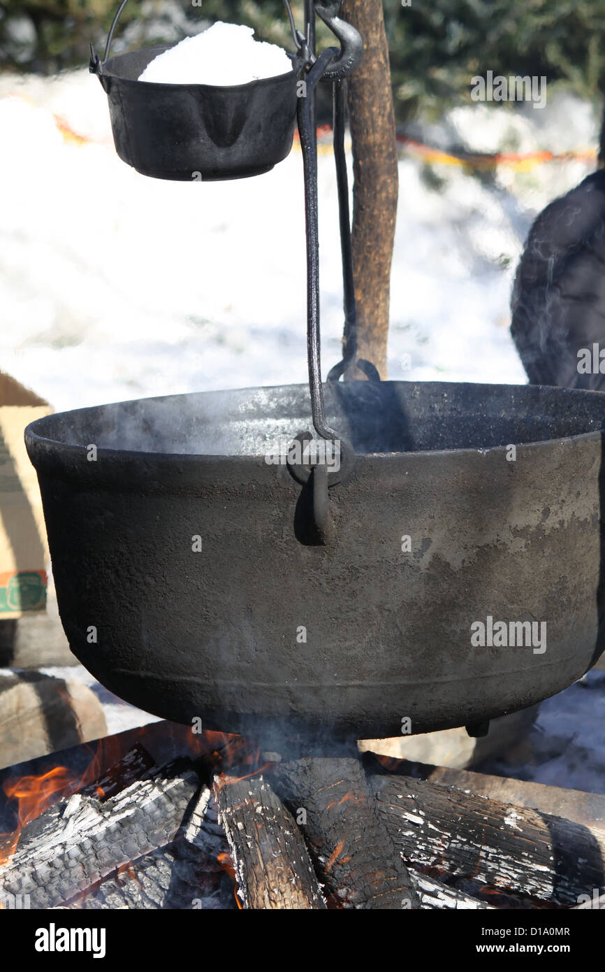 Big kettles over an open wood fire, boiling maple sap outdoors to