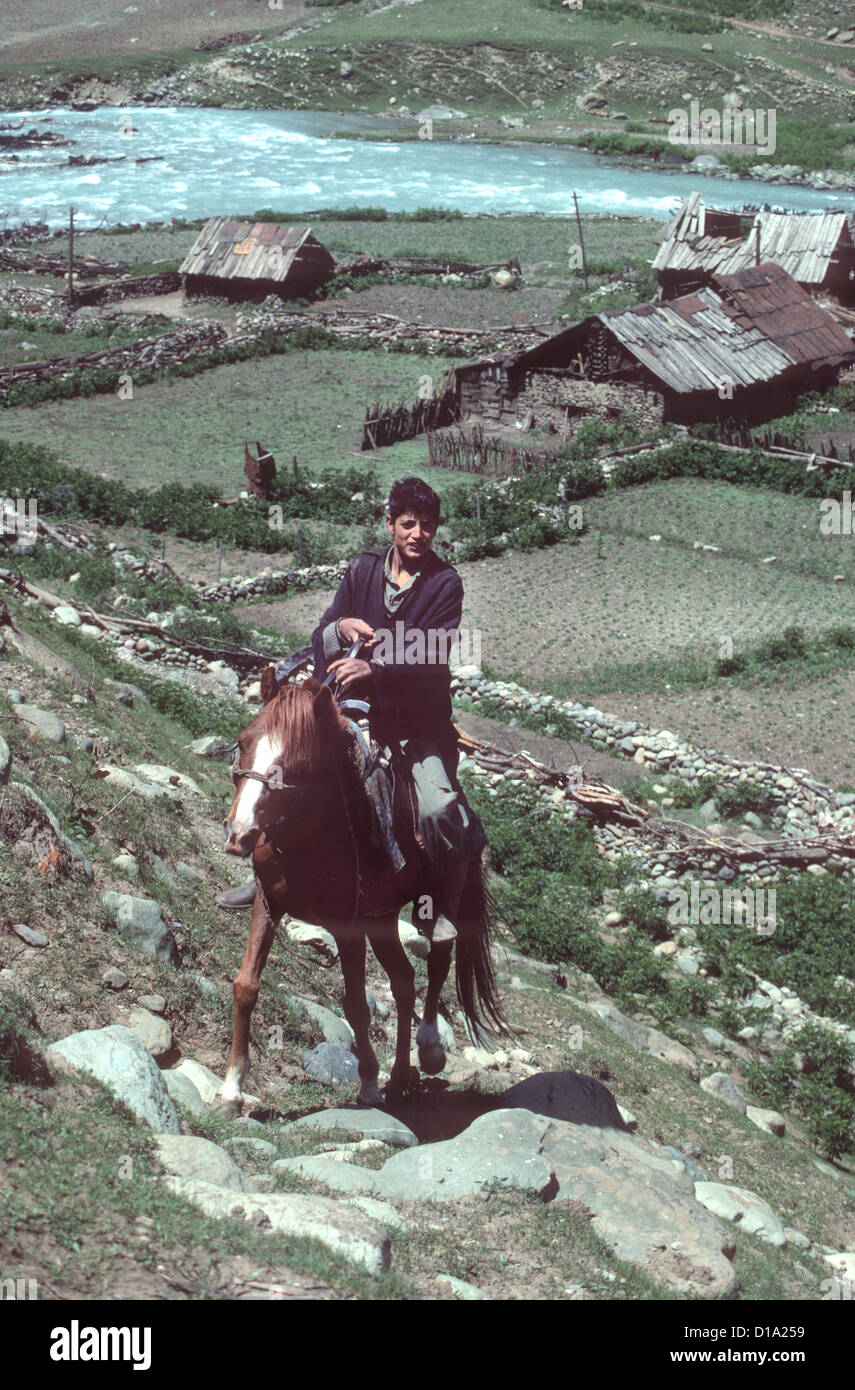 Kashmir - young horseman rides up steep hill from his village beside the Sind River in the Himalayan foothills. Stock Photo