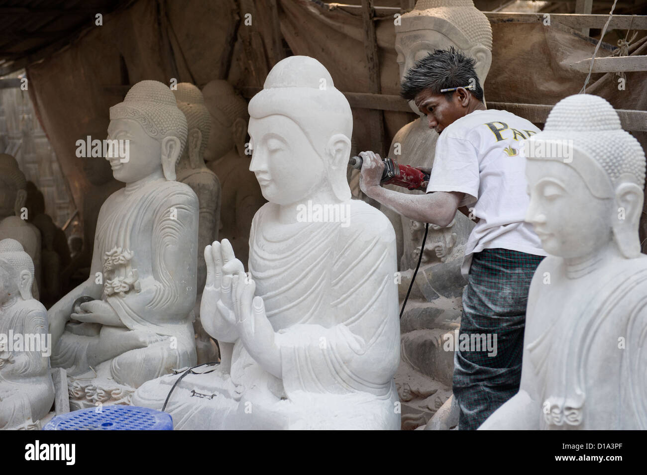 A sculptor carving a Buddha statue on Kuauk Sit Tan Street in the Chanmyathazi area of Mandalay surrounding the Mahamuni Temple. Myanmar, Burma Stock Photo