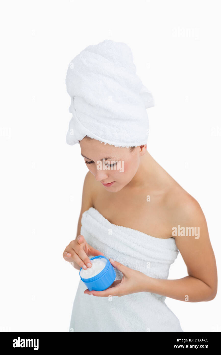 Young woman wrapped in towel applying cream Stock Photo - Alamy