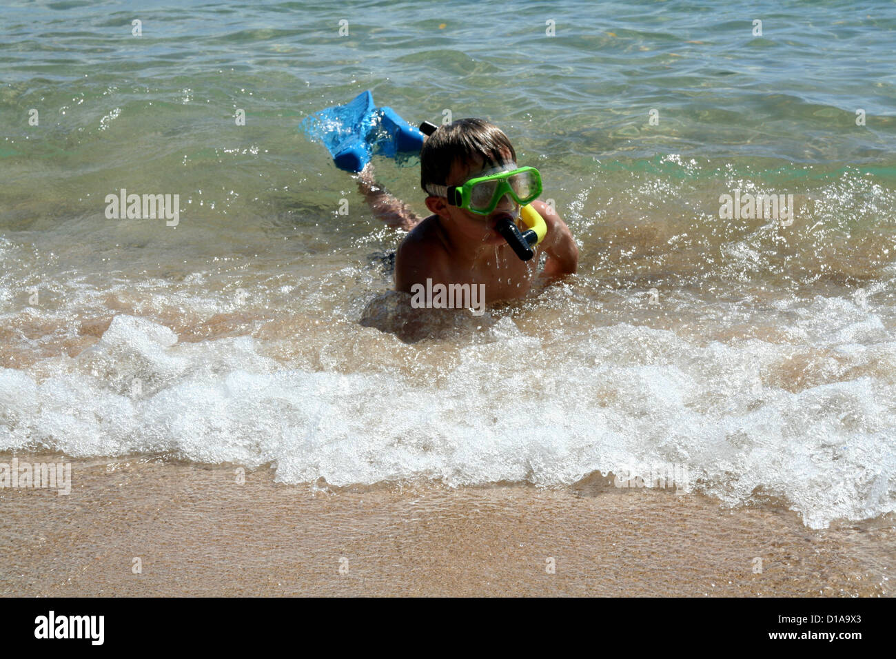 Boy body surfing in from snorkeling in clear blue ocean water Stock Photo