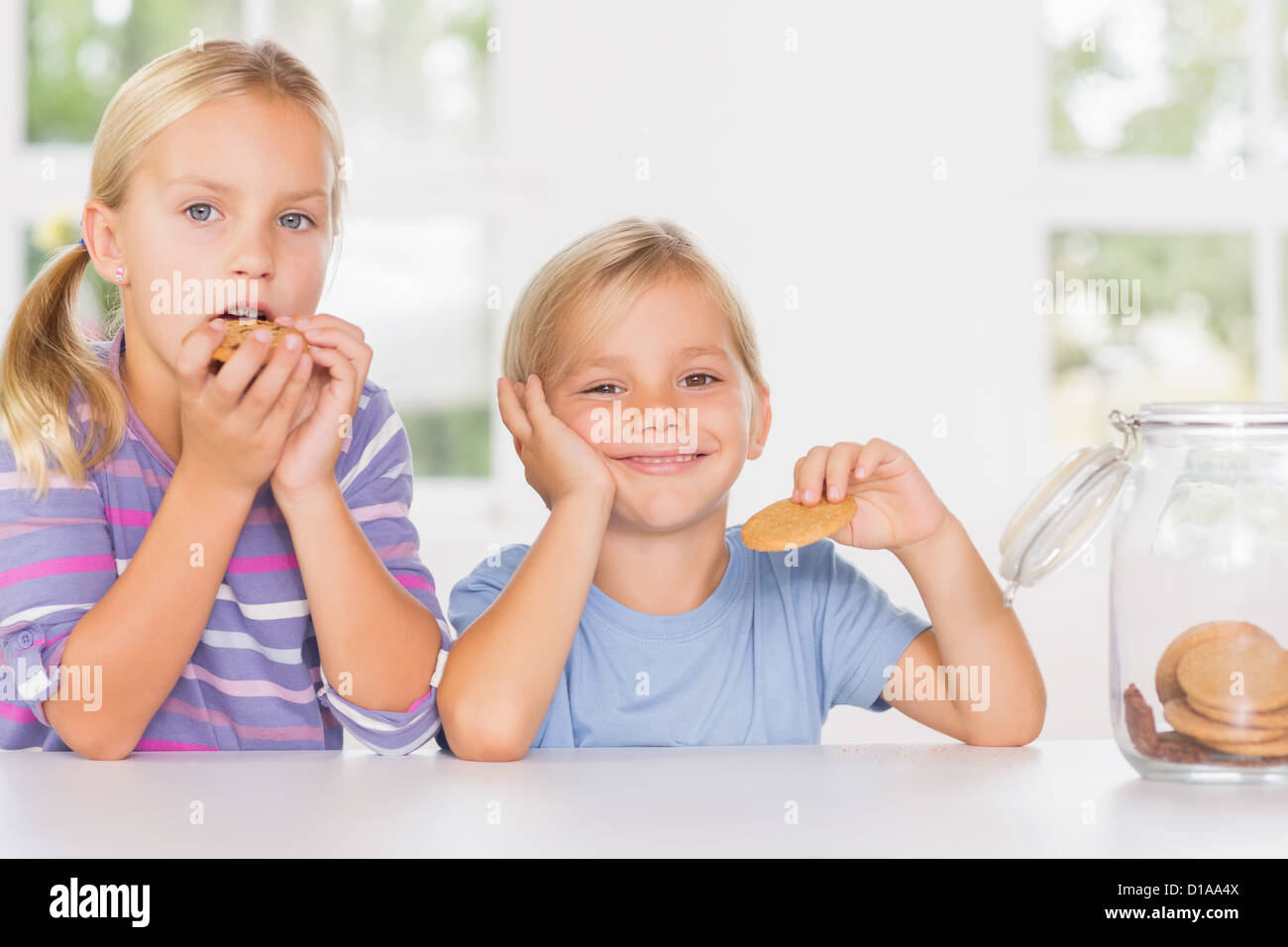 Brother and sister eating biscuits together Stock Photo Alamy
