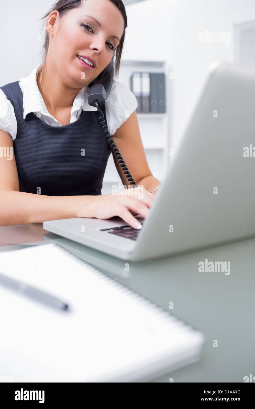 Business woman using landline phone and laptop Stock Photo