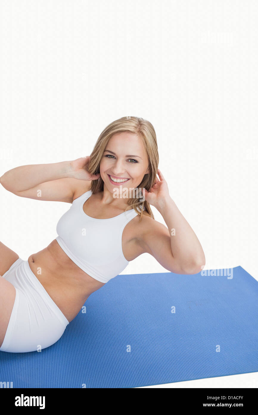Portrait of happy young woman doing situps on exercise mat Stock Photo