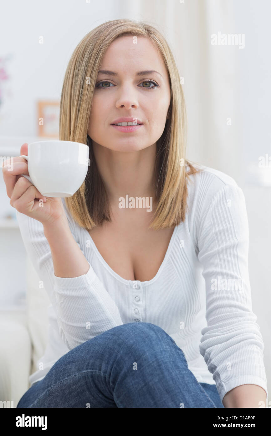 Young woman with coffee cup sitting on couch Stock Photo - Alamy