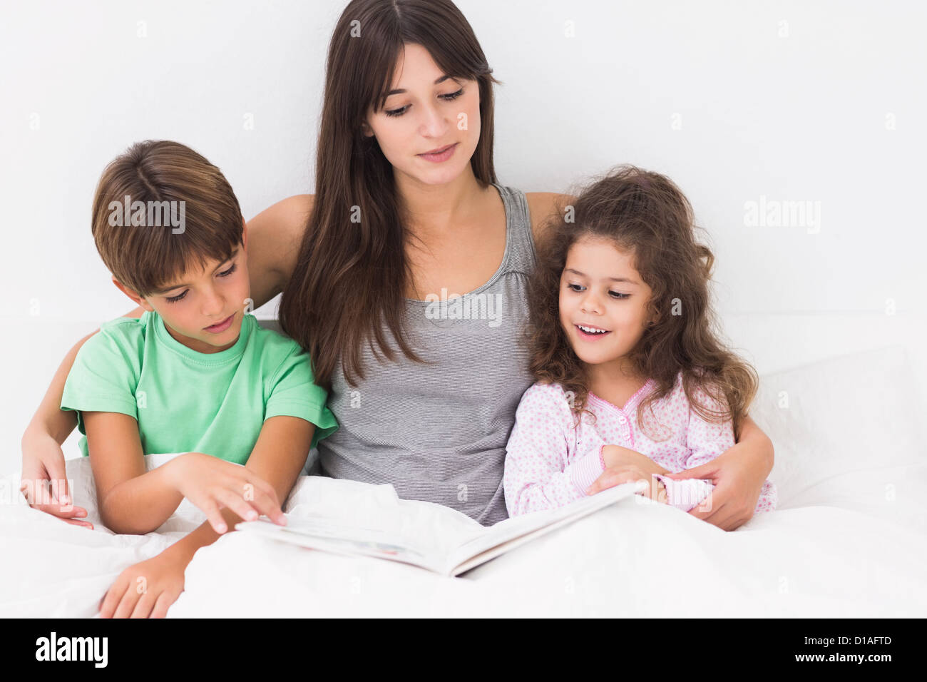 Mother and children reading storybook Stock Photo - Alamy