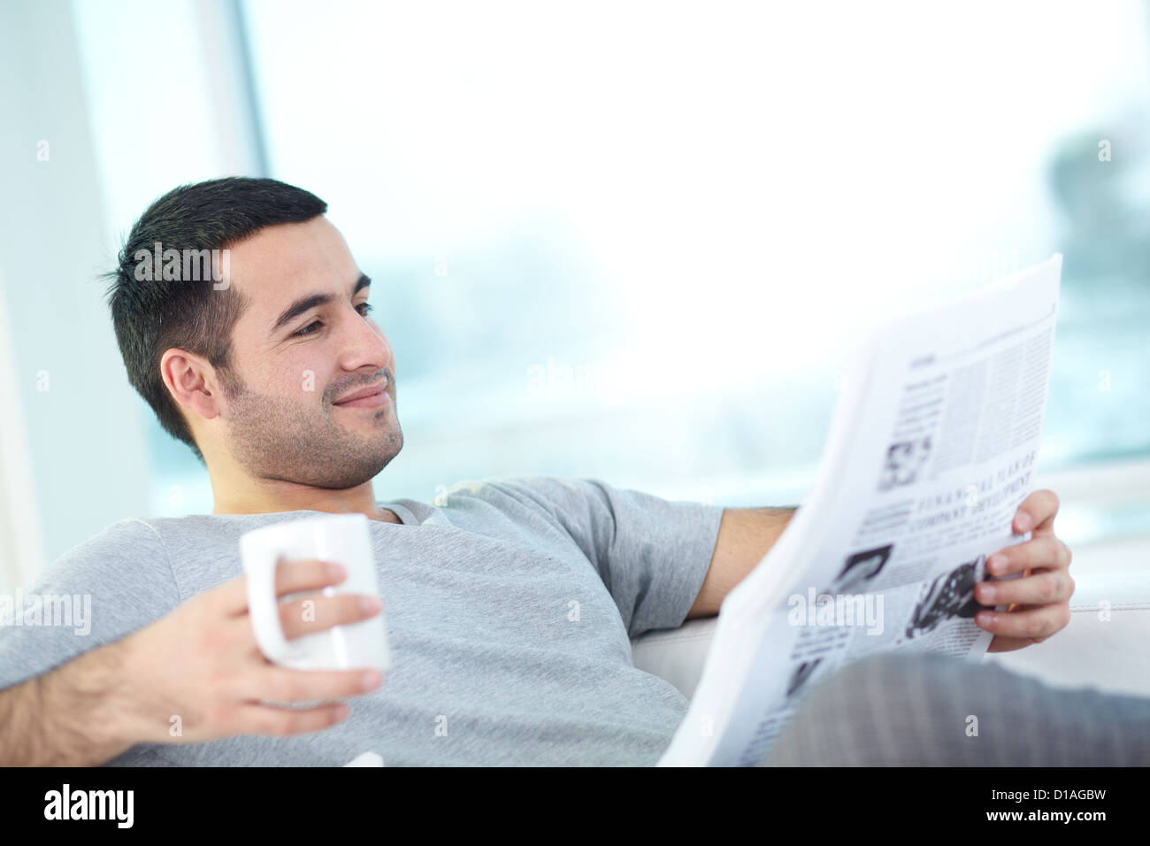 A young guy with newspaper reading it Stock Photo - Alamy
