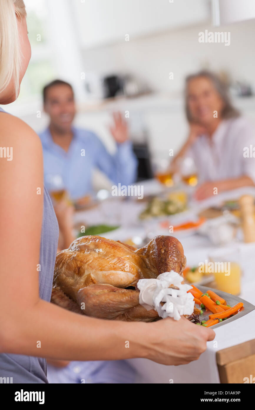Woman bringing the turkey to the dinner table Stock Photo