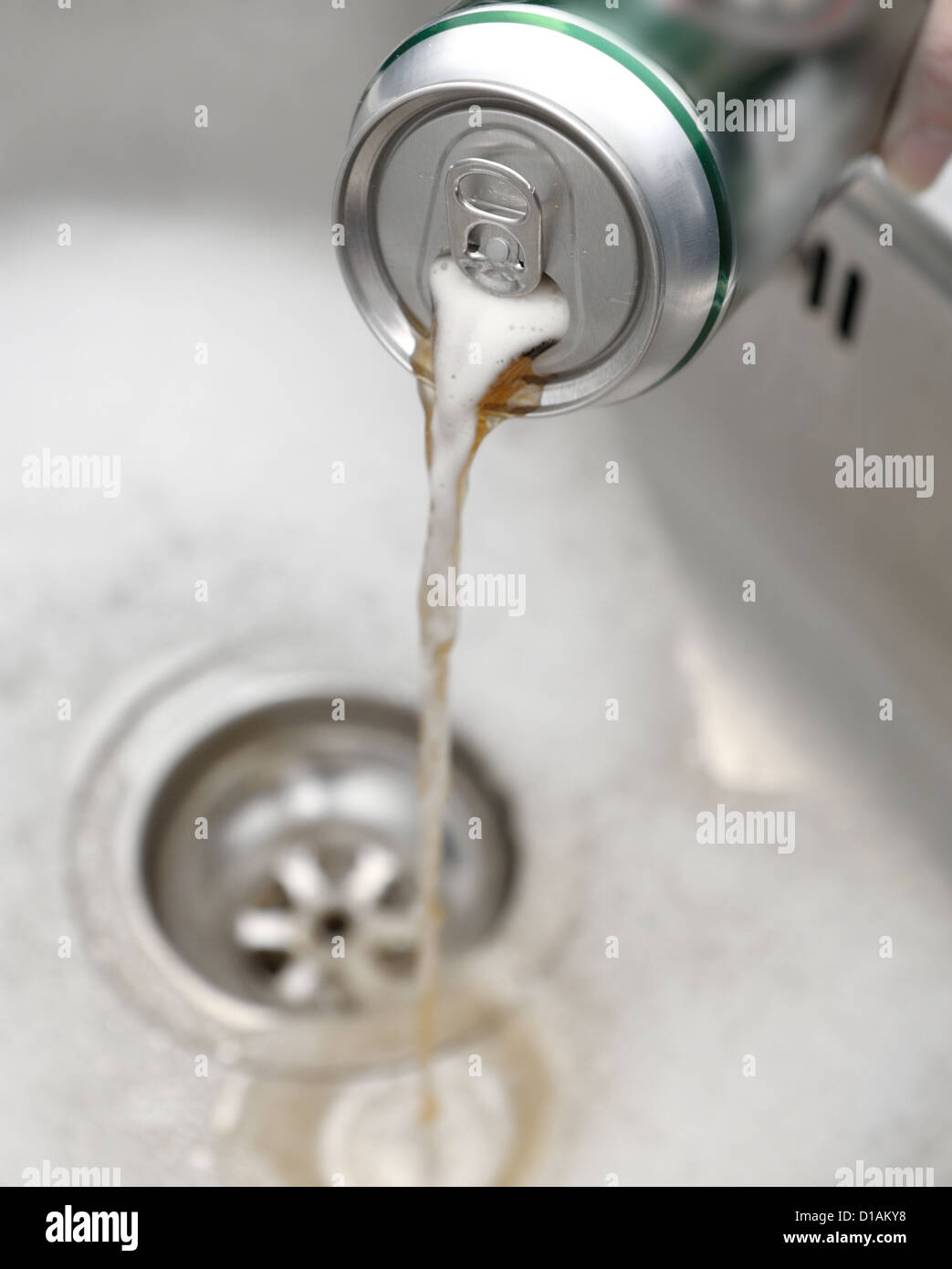 pouring cans of beer down the sink (cans digitally blurred to hide brand logos) Stock Photo