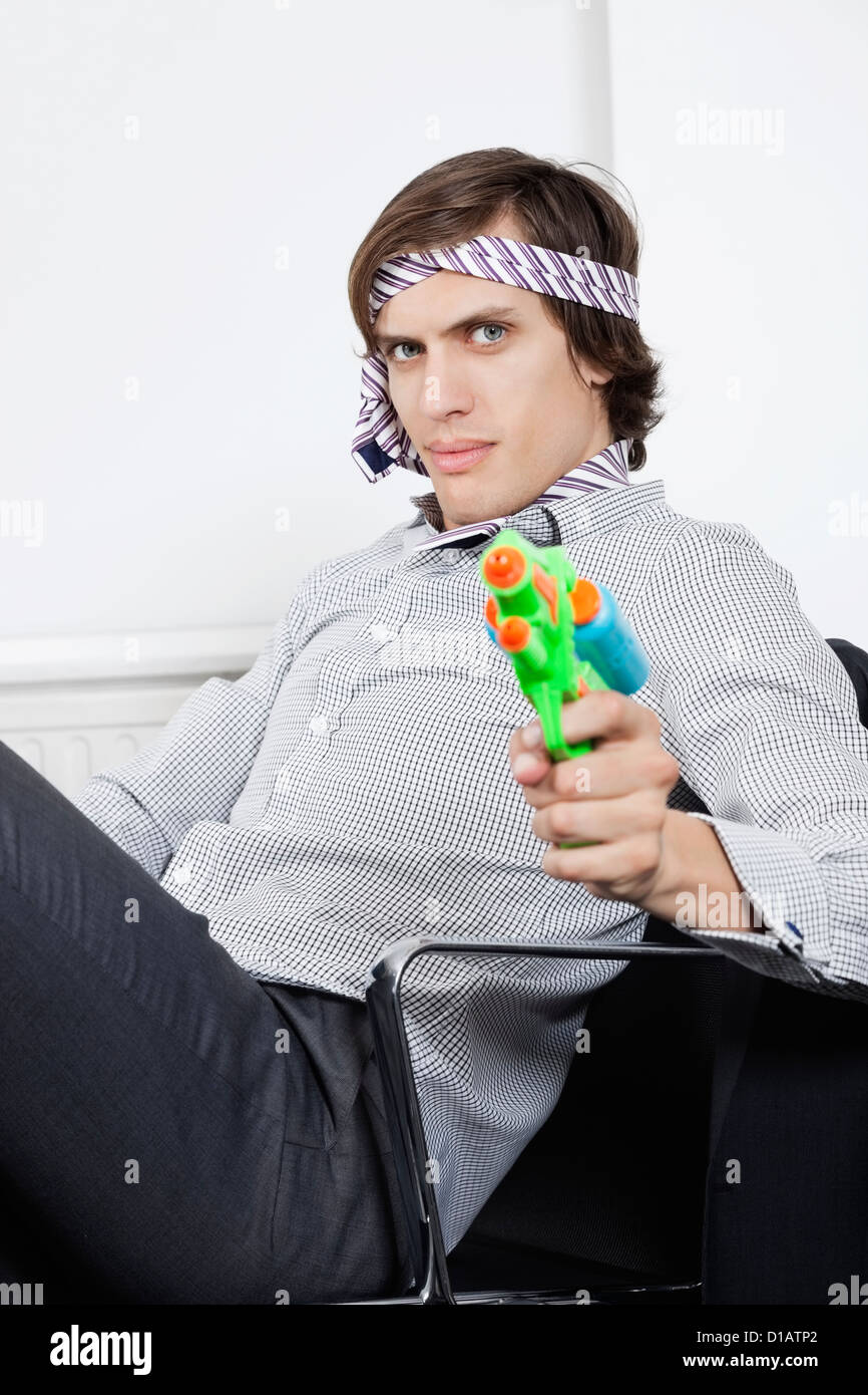 Portrait young businessman holding toy gun Stock Photo