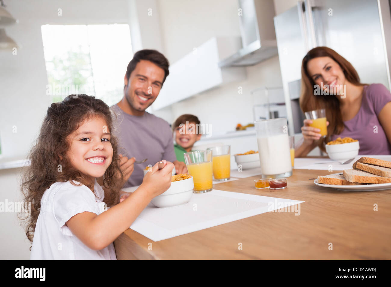 Family smiling at the camera at breakfast Stock Photo - Alamy
