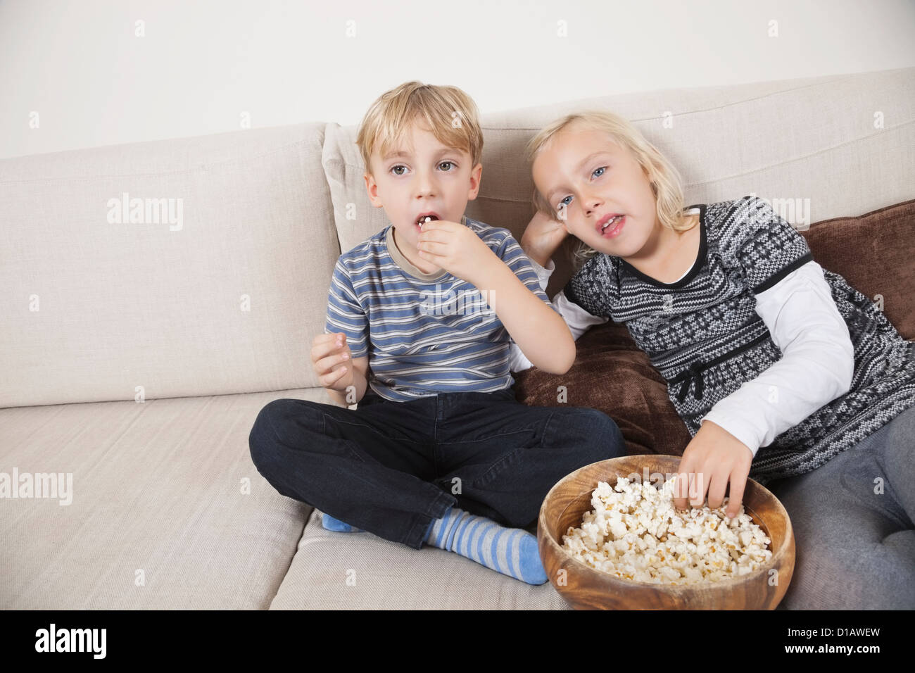 brother sister watching TV eating popcorn Stock Photo