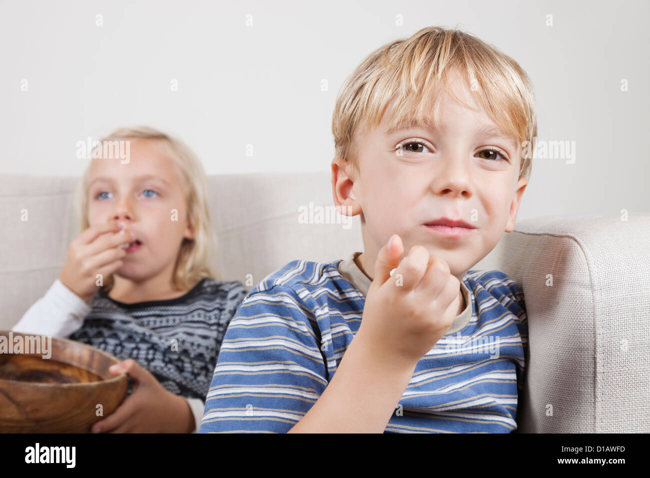 Portrait young boy sister watching TV eating popcorn Stock Photo