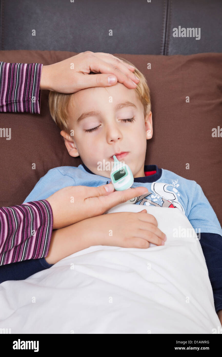 mother checking unwell little boy's temperature rmometer Stock Photo