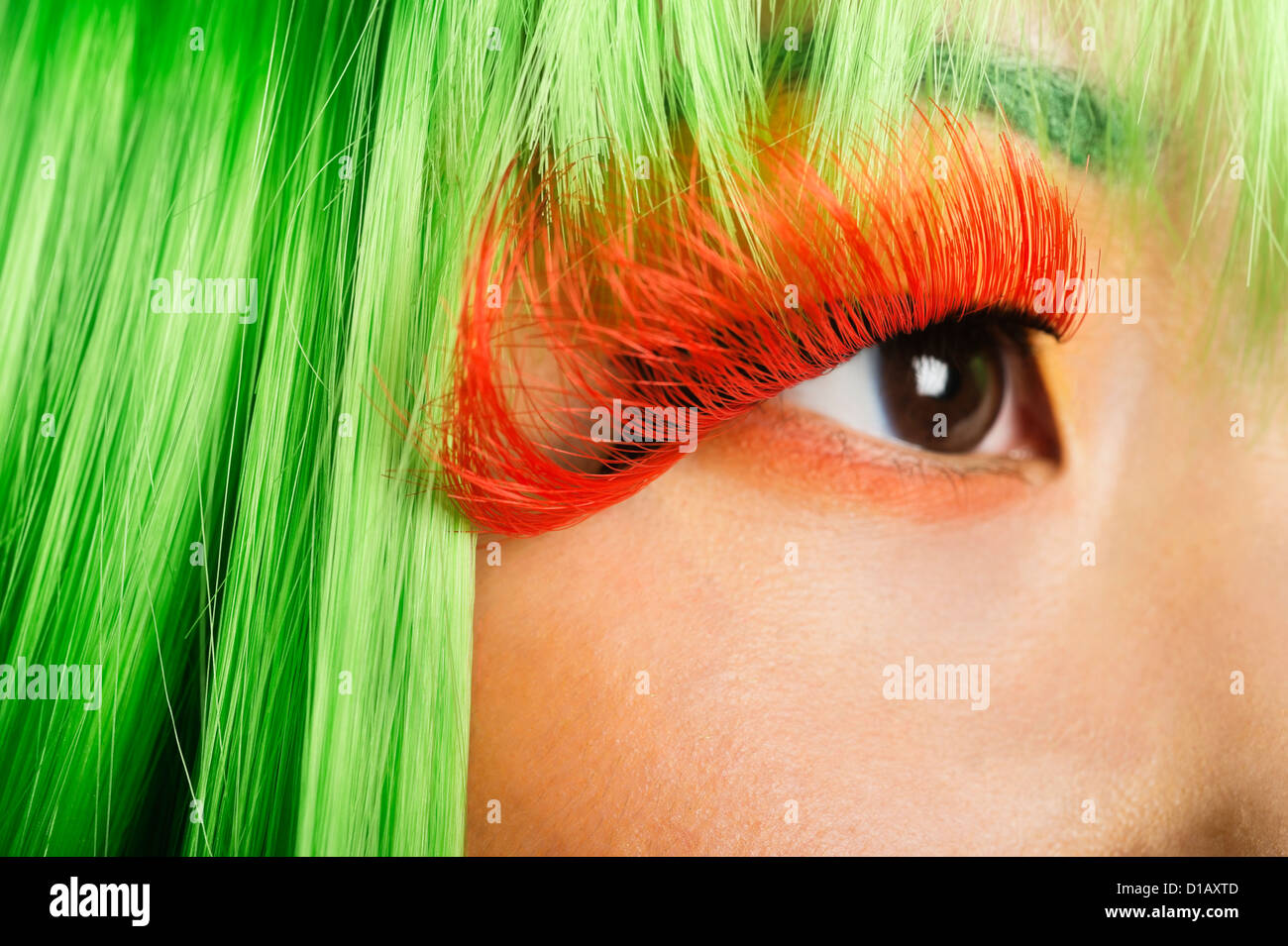 Extreme young woman's face false eyelashes green wig Stock Photo