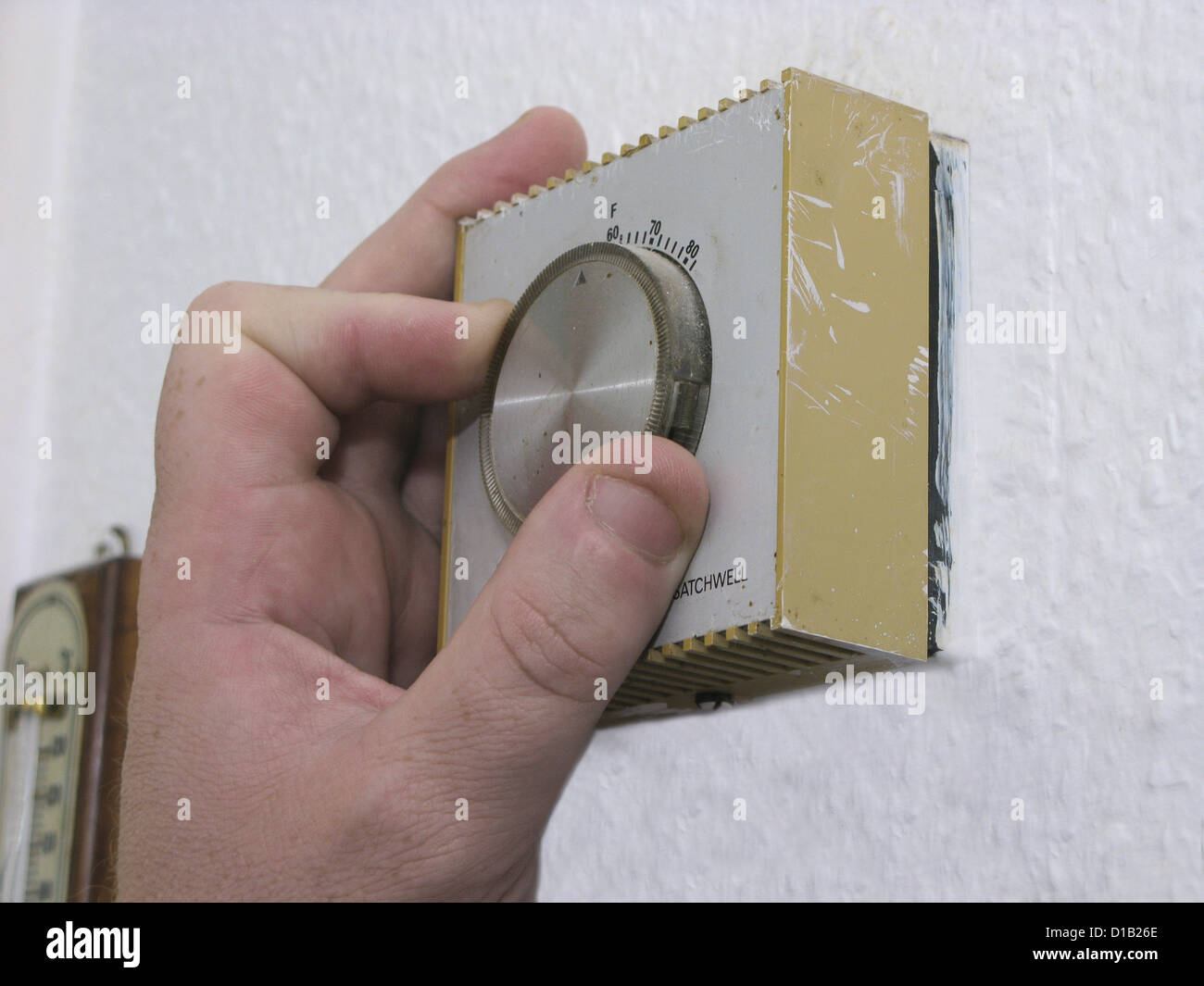 Energy efficiency - man lowering the thermostat on the central heating control to combat global warming and climate change Stock Photo