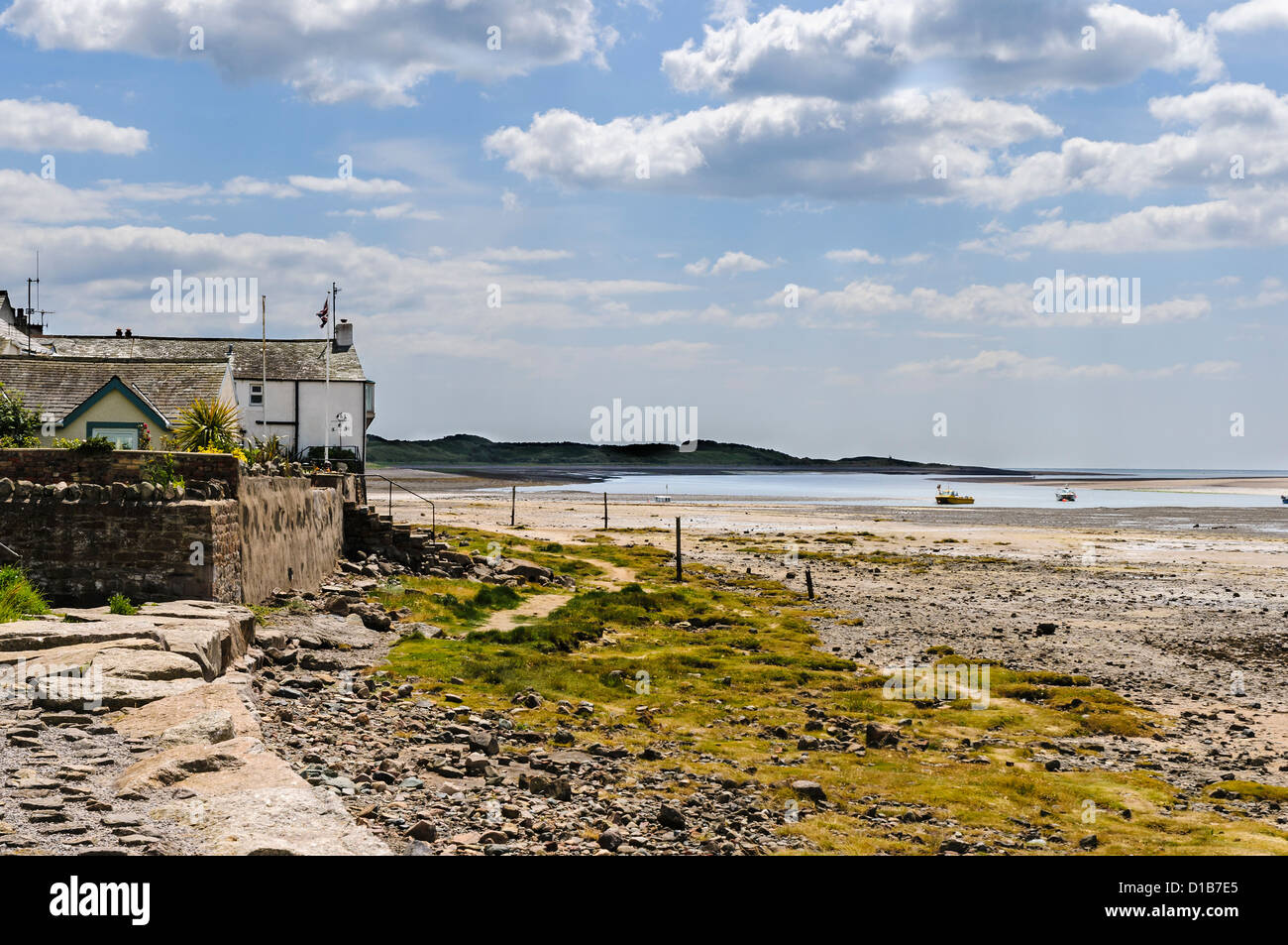 Stone steps lead from whitewashed houses to a stone covered beach and the blue sea in the distance, Ravenglass Stock Photo
