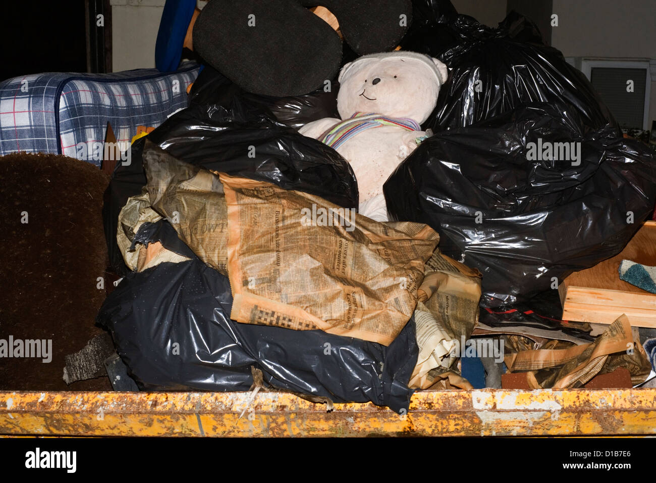 large skip full of household domestic rubbish with discarded soft toy in midst Stock Photo