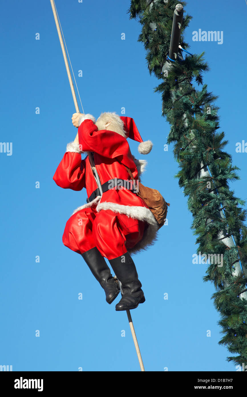 Model of Father Christmas with sack of presents climbing up rope at Bournemouth Town Centre in December Stock Photo