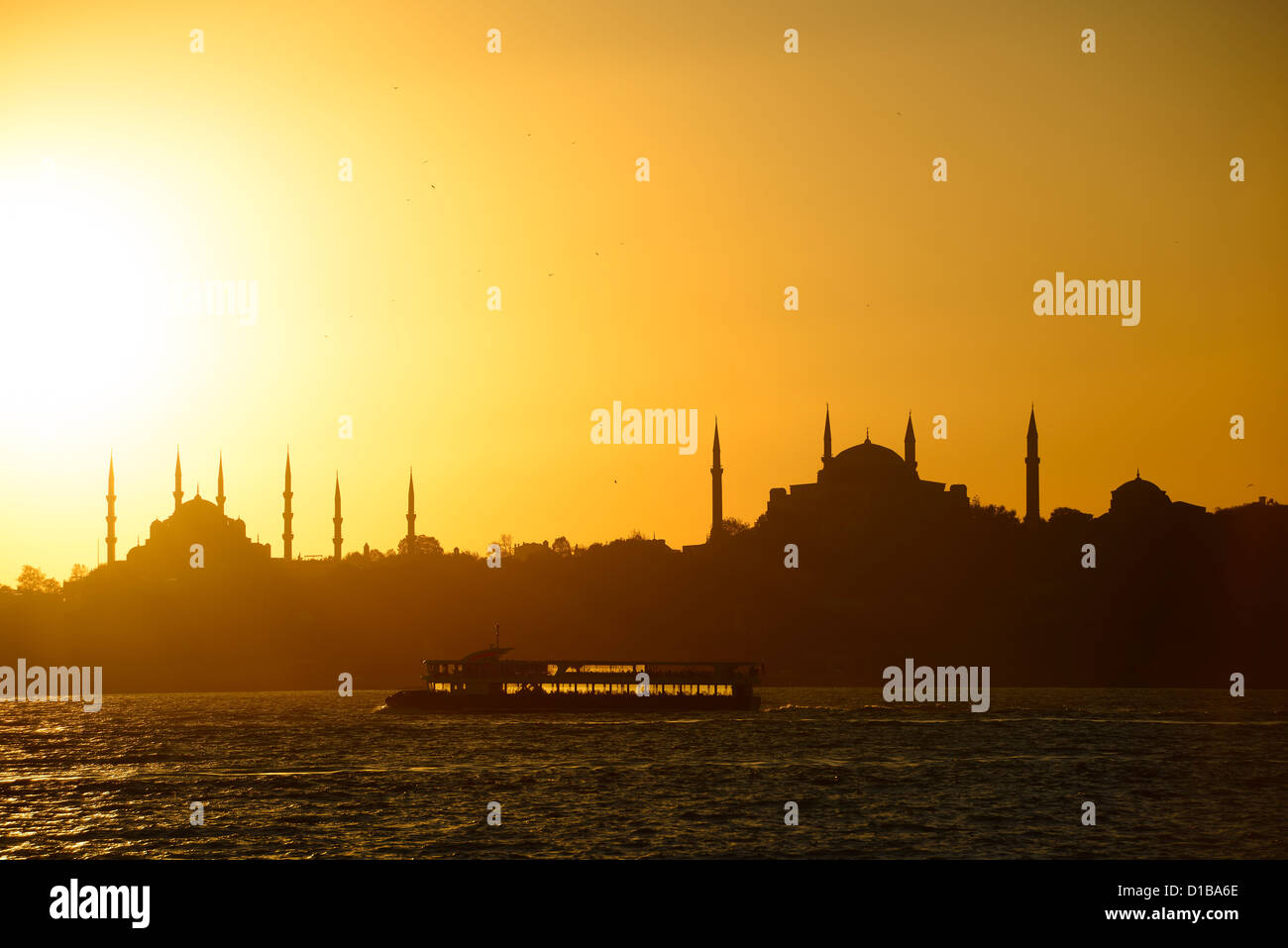 Blue Mosque and Hagia Sophia minarets silhouettes at sundown over the Bosphorus with backlit boat Istanbul Turkey Stock Photo