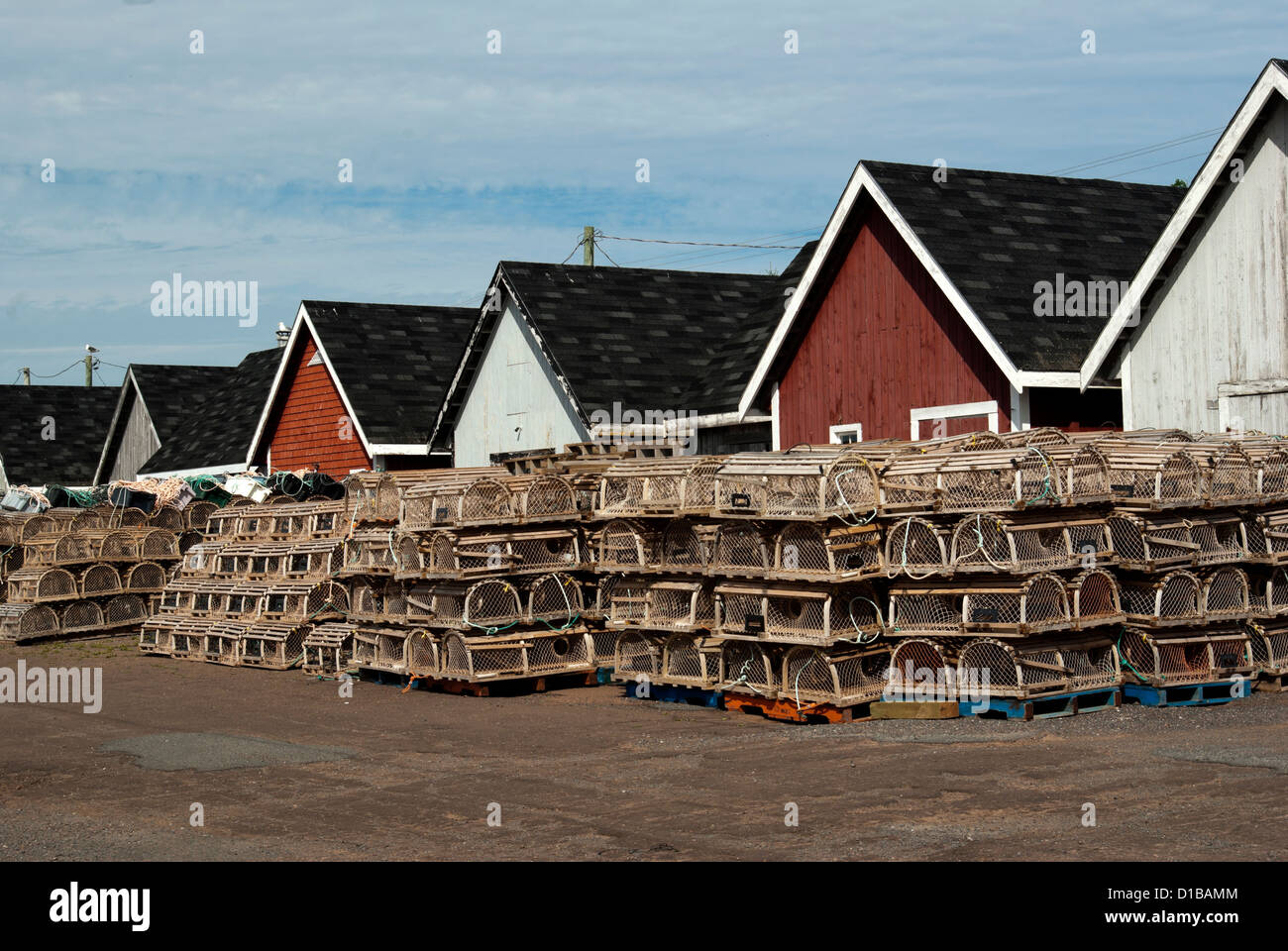 Brightly coloured fish houses and stacks of lobster traps on harbour's edge Stock Photo