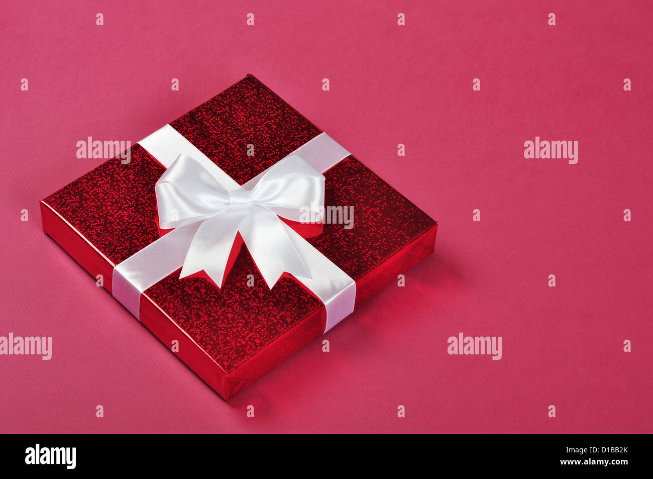 red gift box with a white bow on red background Stock Photo - Alamy