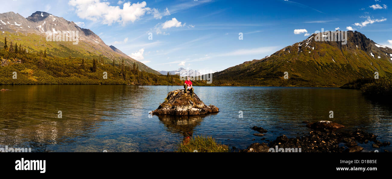 Woman sitting on the rock in the middle of the Paradise Lake in Alaska. Stock Photo