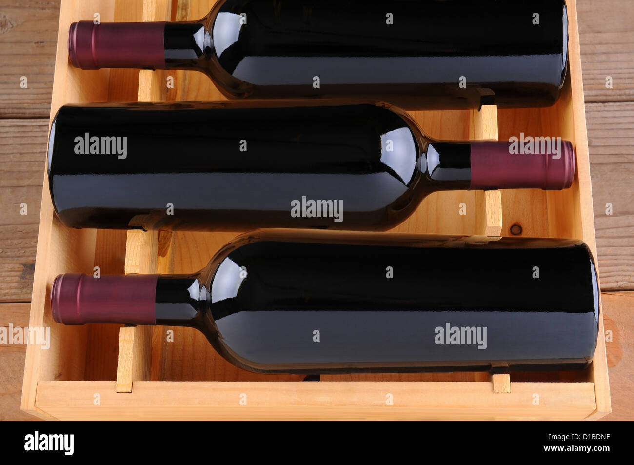 Three red wine bottles in a wooden case, isolated on white, Vertical Format. Stock Photo
