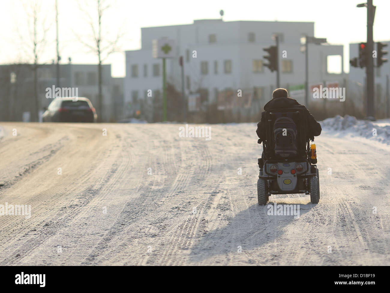 A man rides over a snowcovered street in an electric wheelchair in