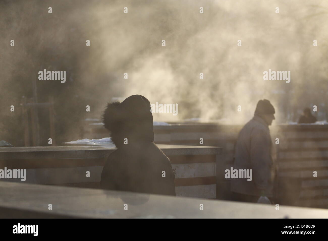 Sofia, Bulgaria; 14th December 2012. People filling their water bottles at the hot mineral water springs in central Sofia. Because the temperature difference between water and air is about 50 degrees large plumes of vapor are covering the area. Credit:  Johann Brandstatter / Alamy Live News Stock Photo