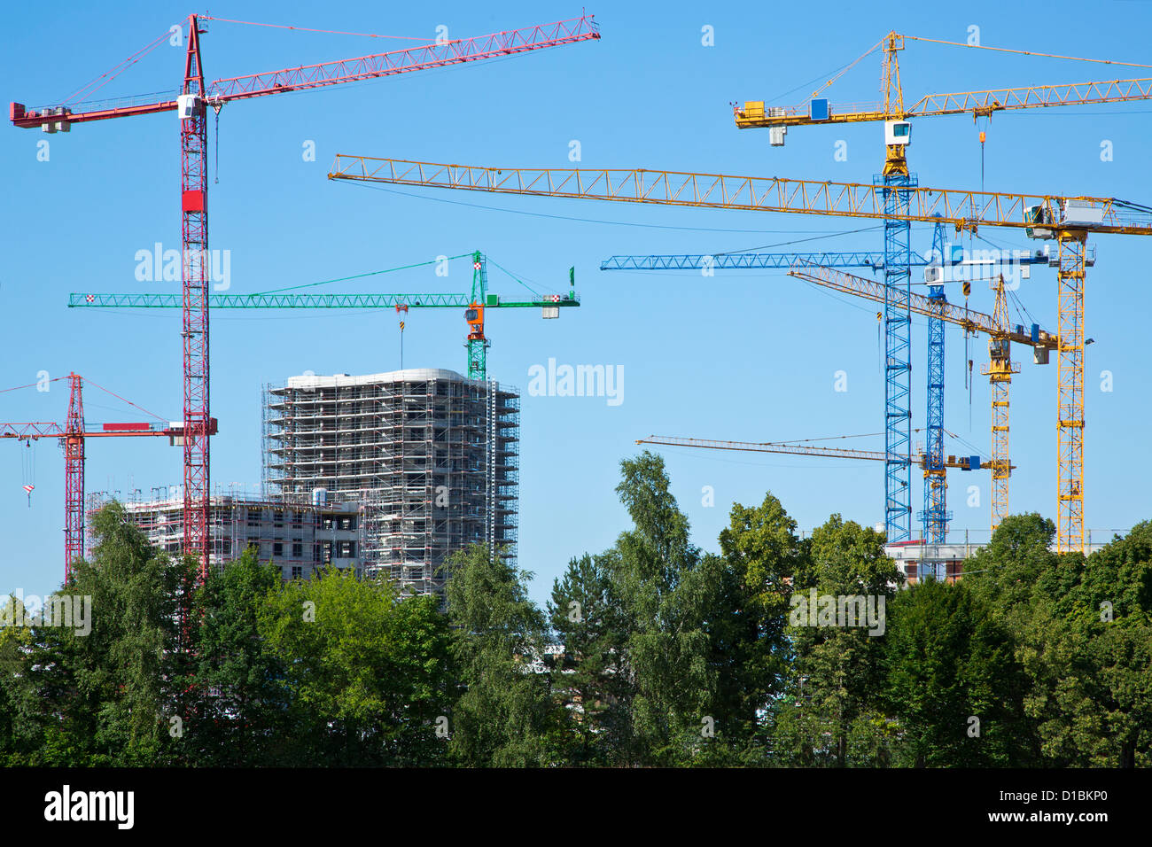 Cranes on a construction site with trees Stock Photo