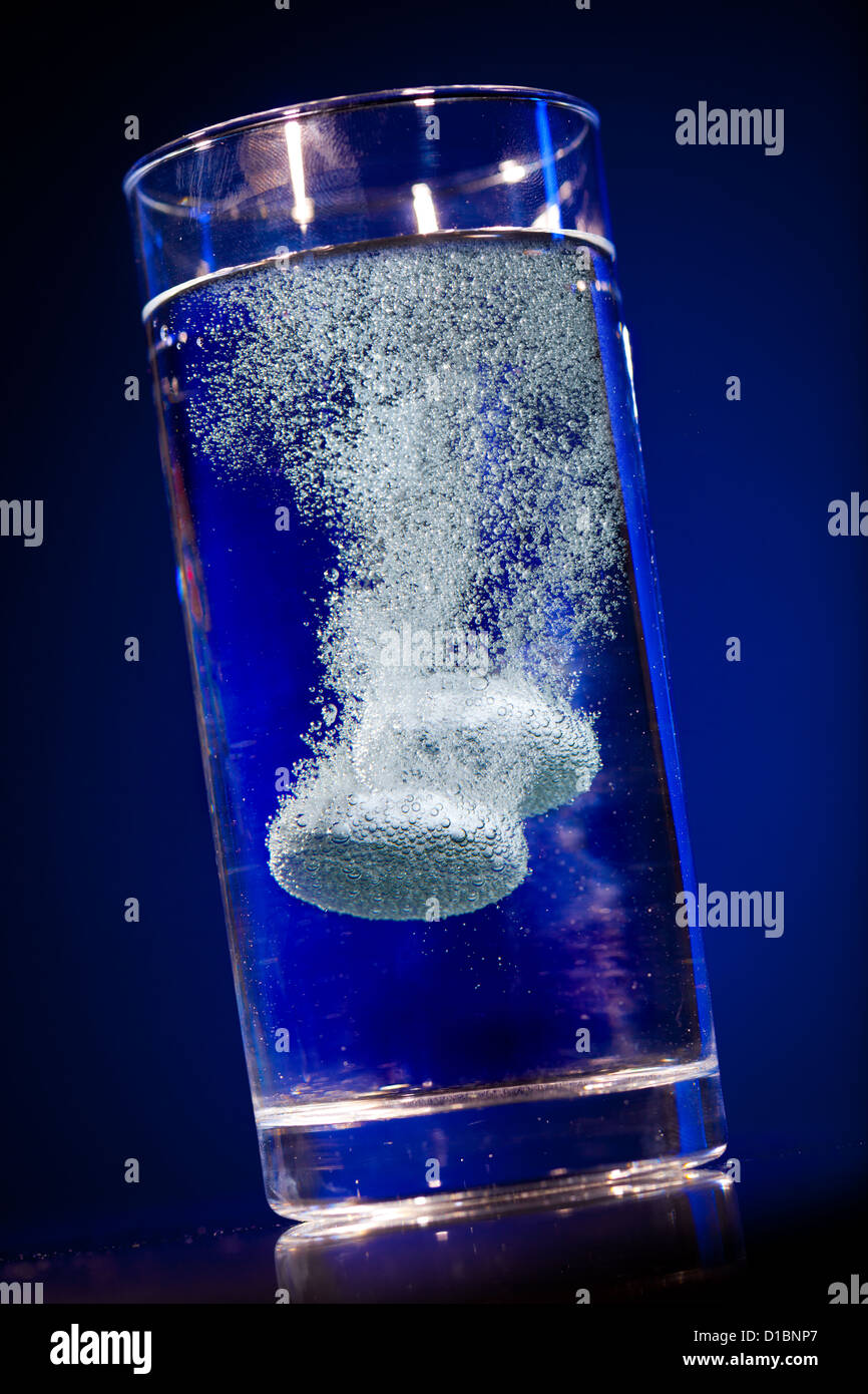 Effervescent tablet in water with bubbles on a blue background Stock