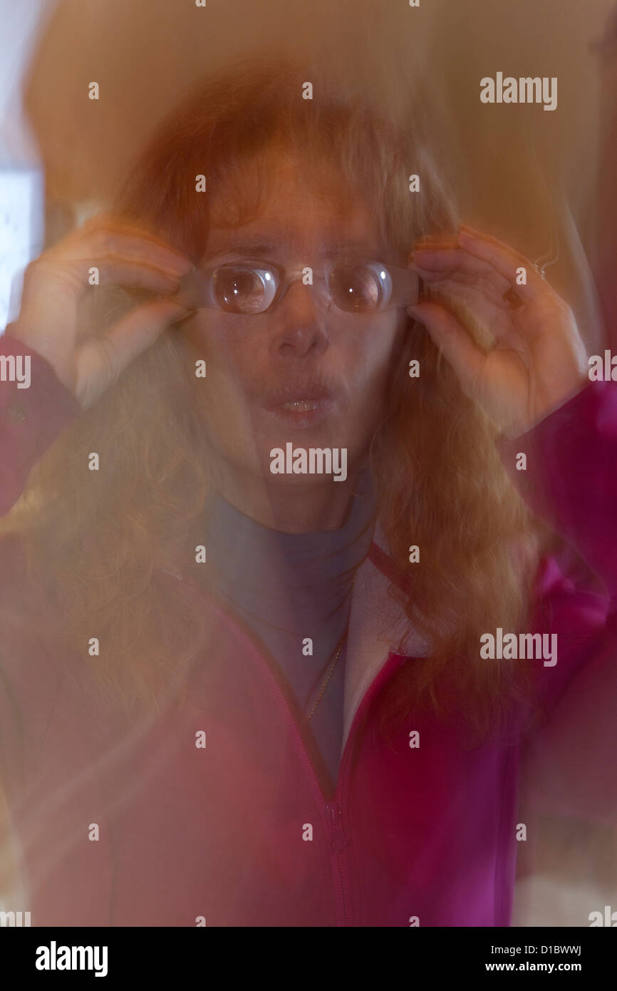 A woman copes with her blurring vision loss with various special classes for assistance reading or watching television Stock Photo