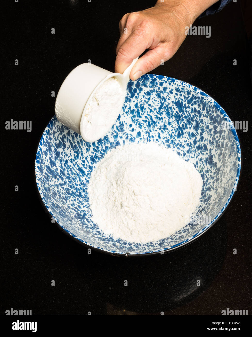 A baker adding ingredients to a mixing bowl Stock Photo