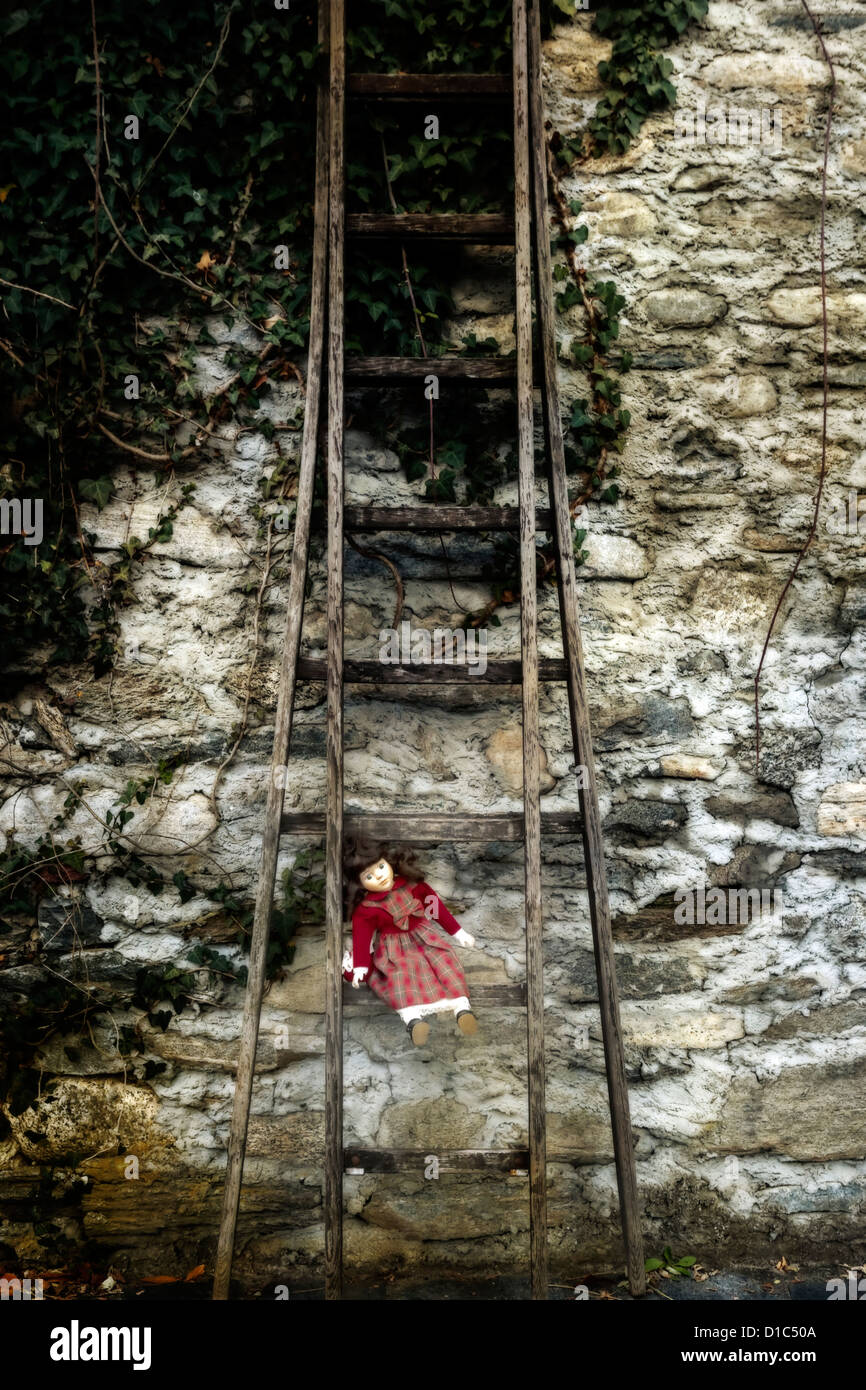 an old doll sitting on an old wooden ladder Stock Photo