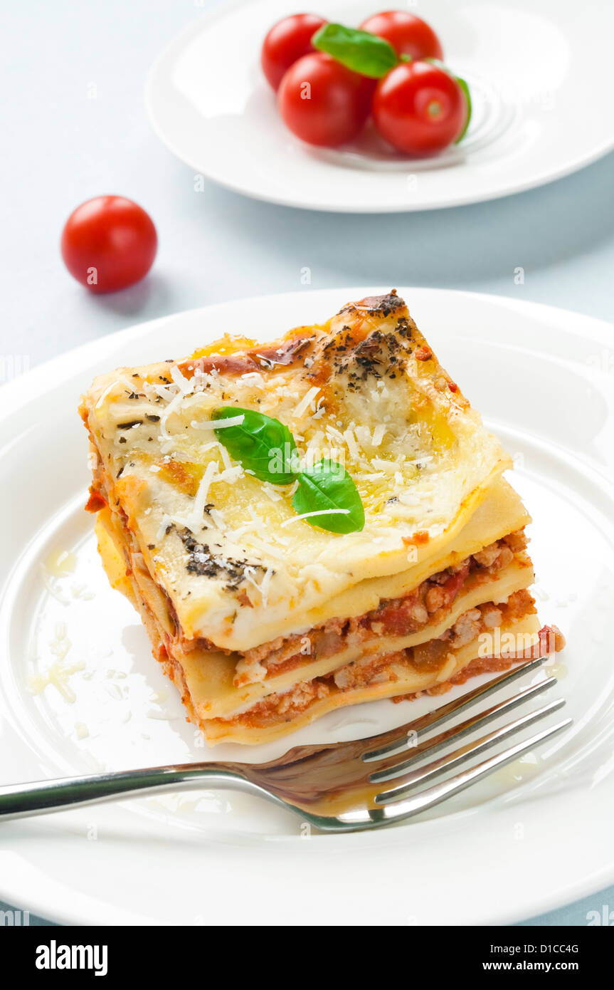 Portion of lasagna with meat topped with parmesan and basil Stock Photo