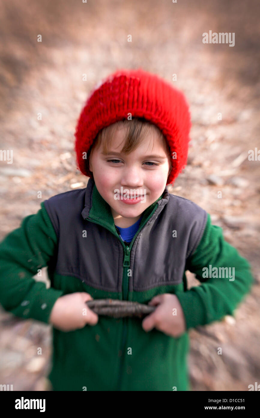 Little boy in fleece and red hat going on a hike and collecting fire wood Stock Photo