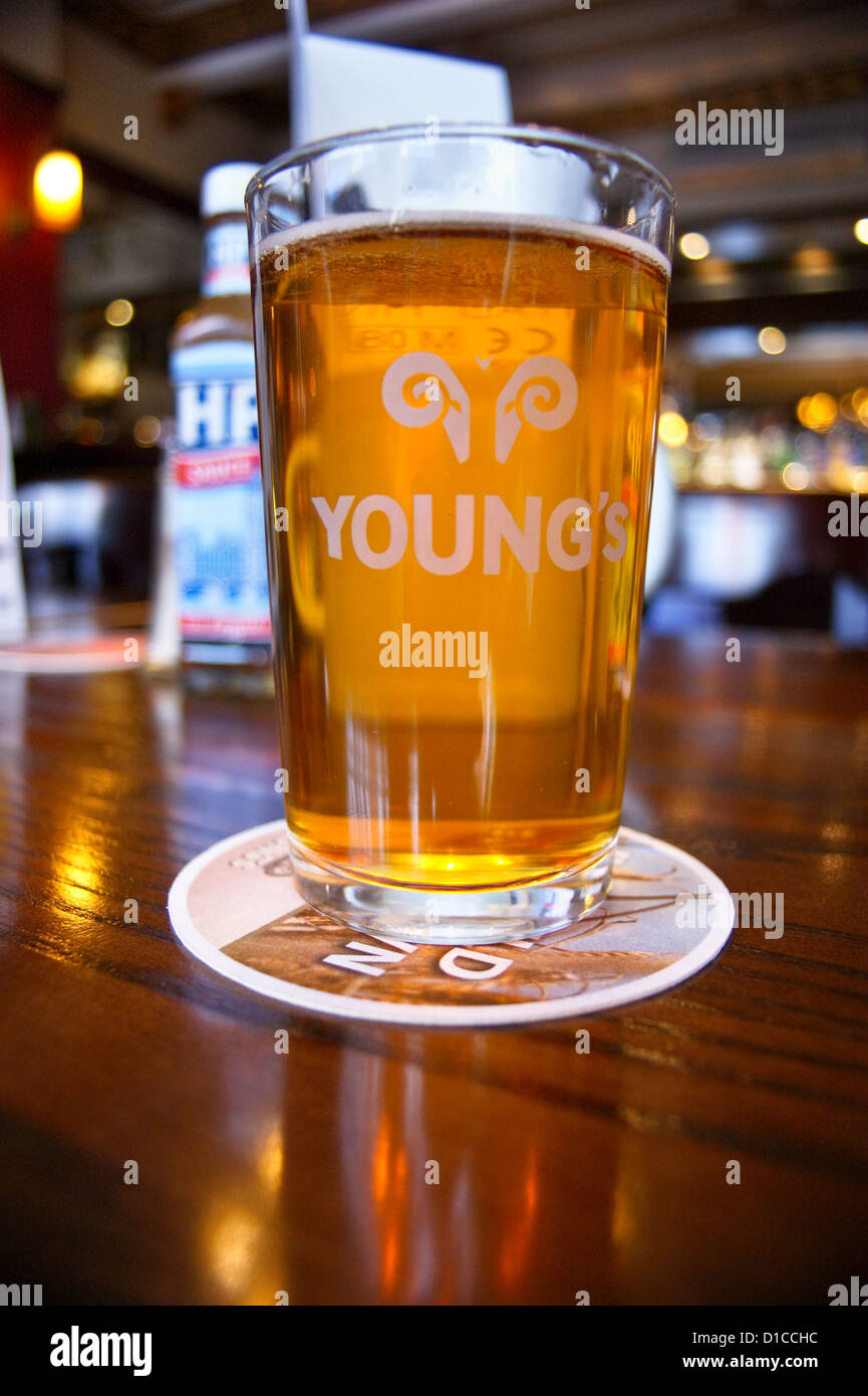 A pint of Youngs ordinary bitter ale with a bottle of HP sauce on a table in an English pub in London, the Guinea Grill, Mayfair, pub table drinks Stock Photo
