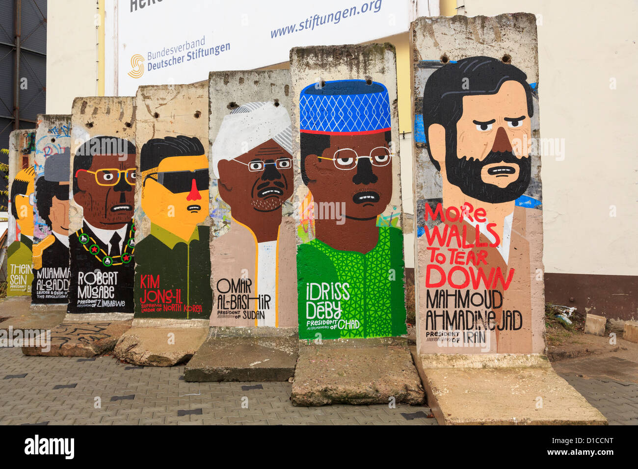 Street scene with remaining sections of the wall painted with murals depicting a portrait of world dictators on Friedrichstrasse, Berlin, Germany Stock Photo
