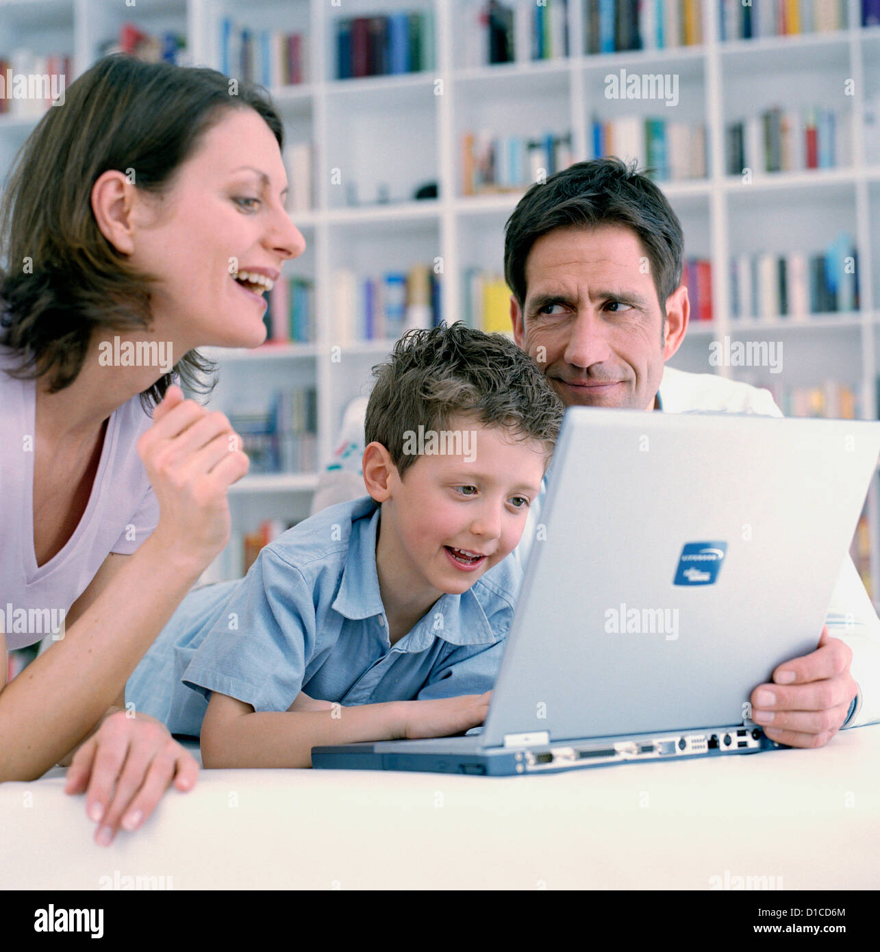 Family in living room with laptop smiling Mother father and son looking ...
