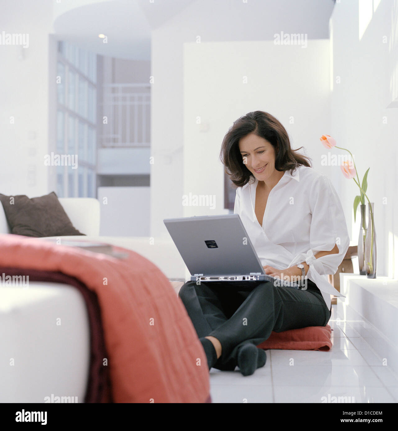 A happy woman surfing on a laptop at home License free except ads and billboards Stock Photo