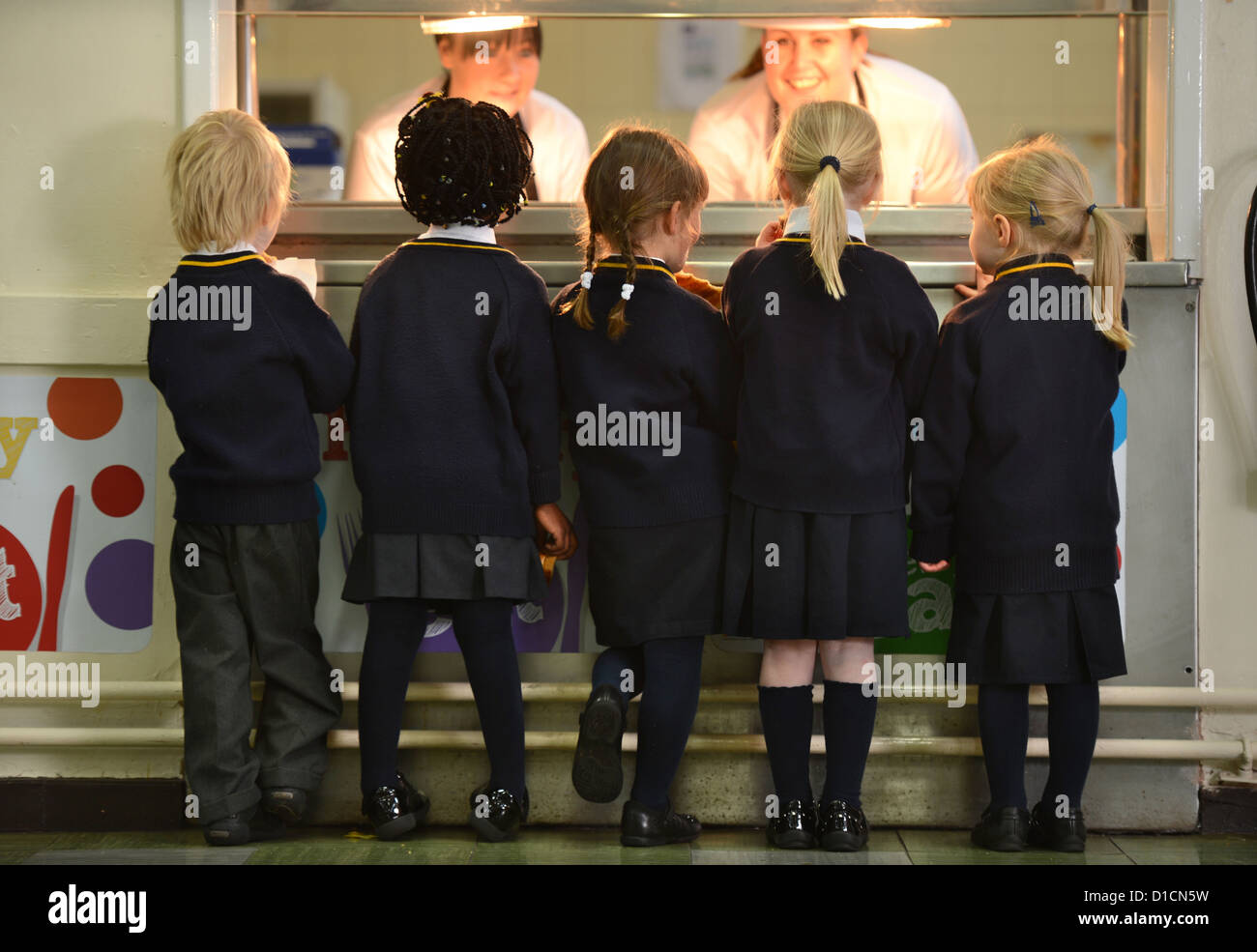 Schoolchildren queuing for toast after morning assembly at Our Lady & St. Werburgh's Catholic Primary School in Newcastle-under- Stock Photo