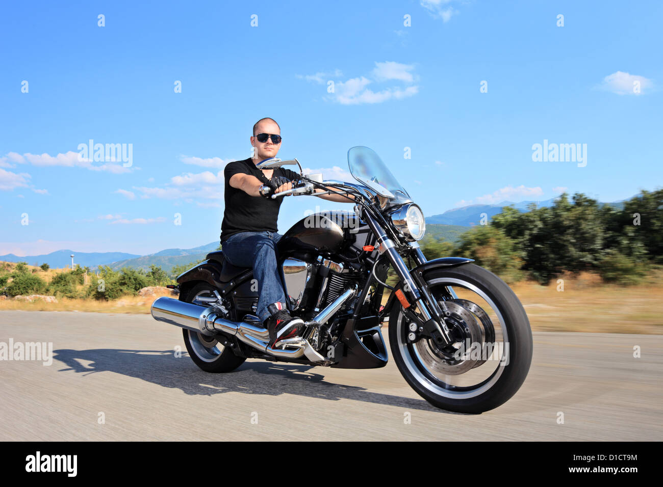 A young biker riding a customized motorcycle on an open road Stock Photo