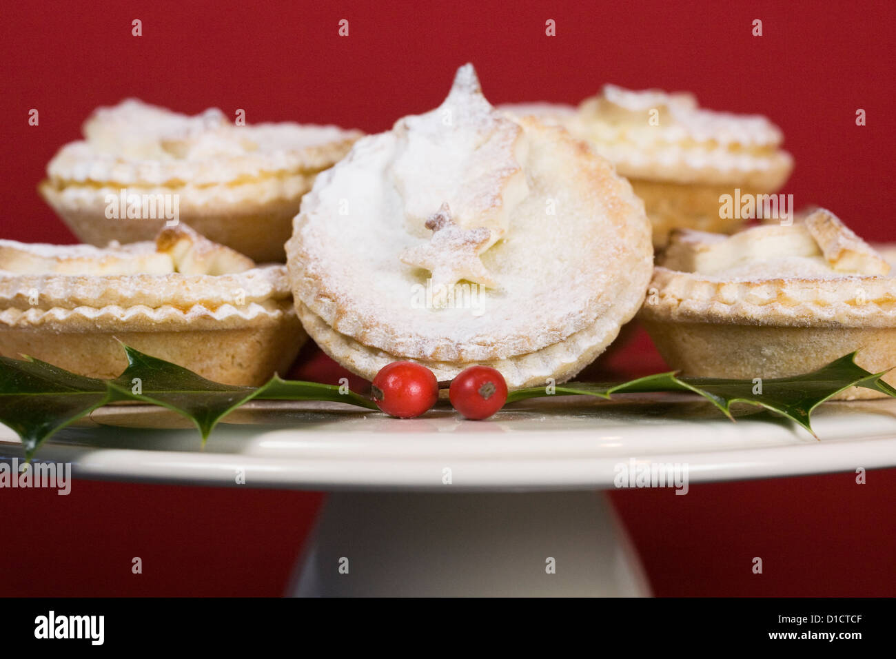 Freshly made mince pies on a cake stand against a red background. Stock Photo