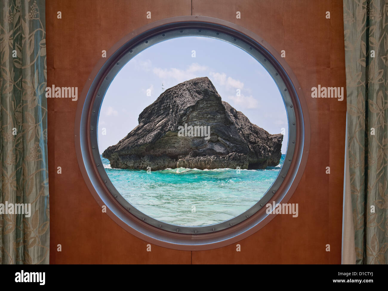 A large rock in the Atlantic ocean in the coastal waters of Bermuda seen through the porthole of a cruise ship. Stock Photo
