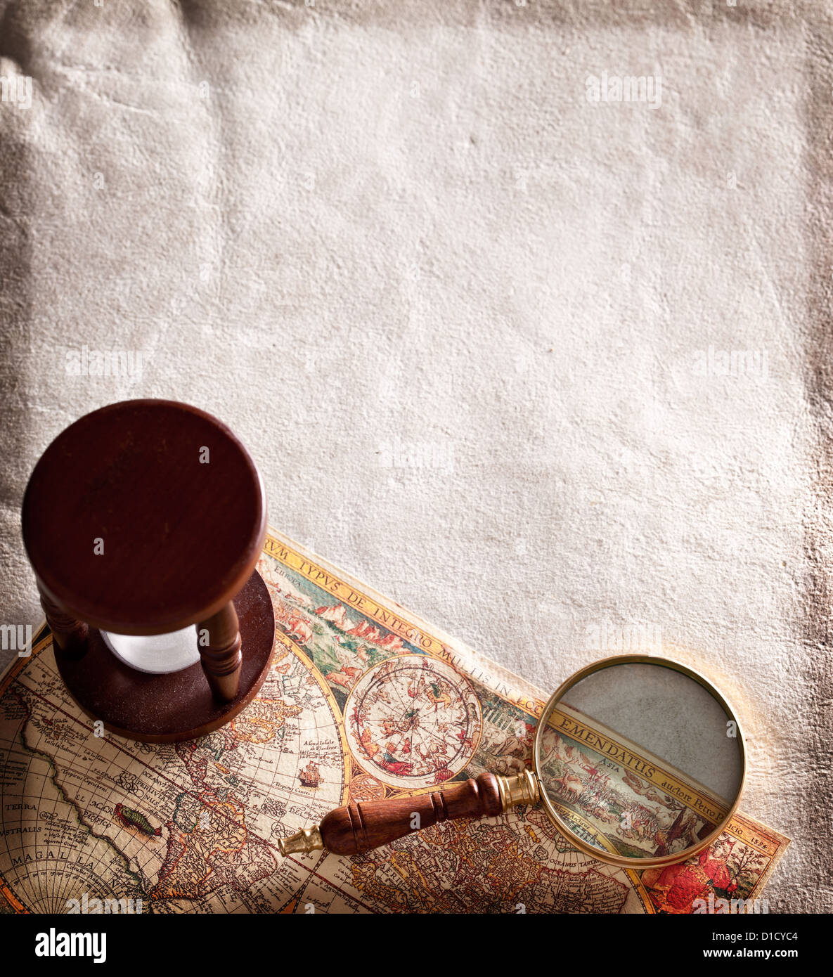Hourglass with a magnifying glass on old parchment. Stock Photo