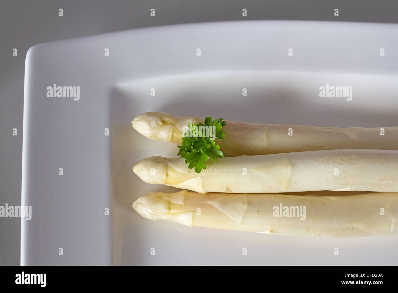 White asparagus with parsley on the edge of a plate Stock Photo