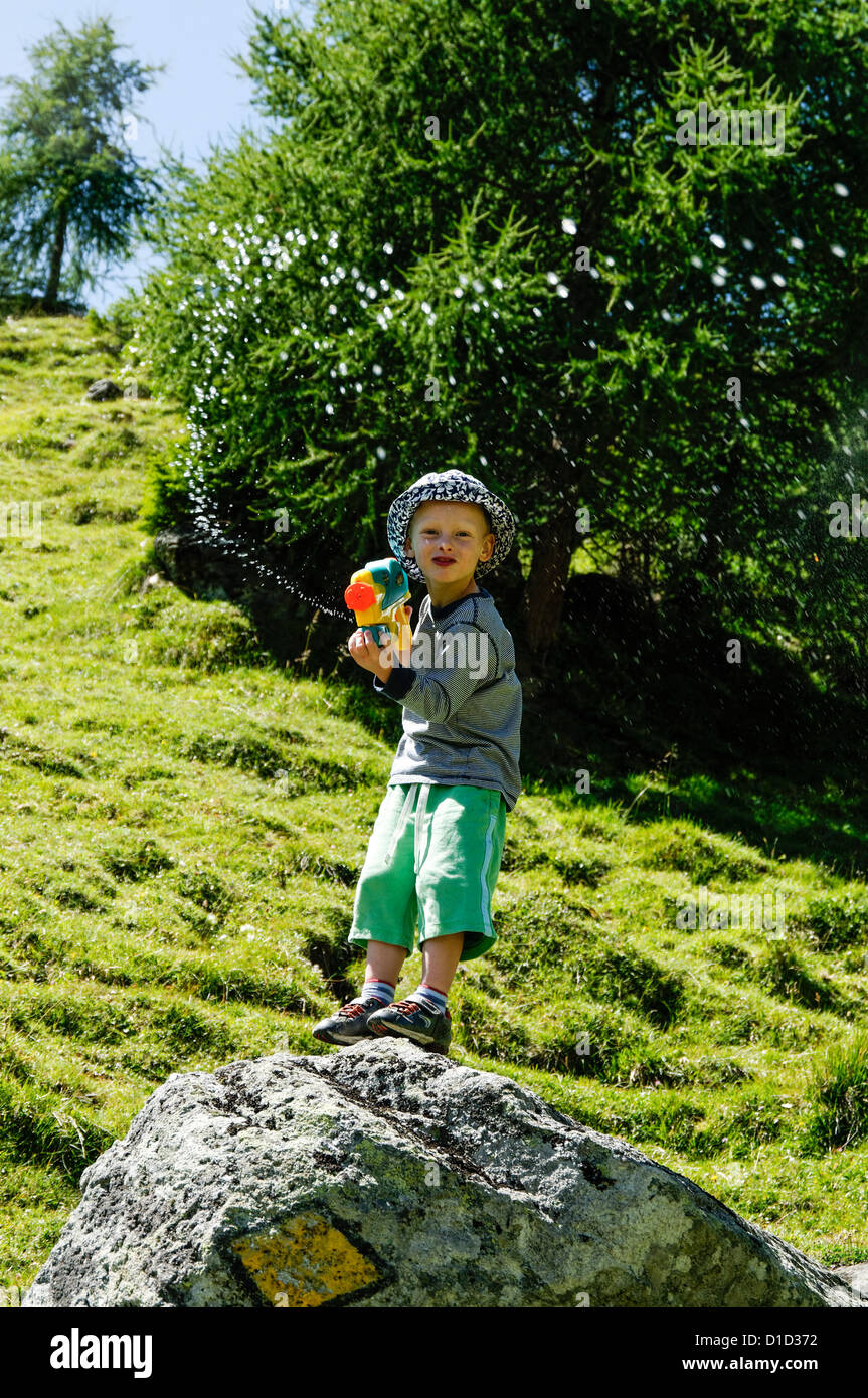 A young boy squirting water from a water pistol Stock Photo