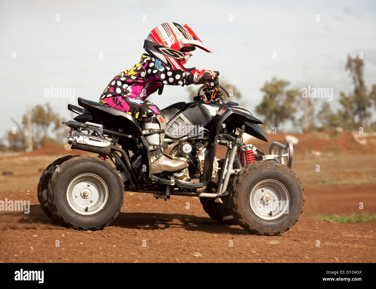 Young child aged four on quad bike wearing protective clothing and