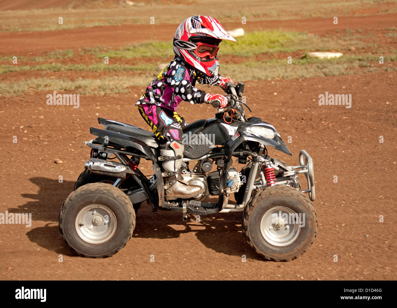 Young child aged four on quad bike wearing protective clothing and